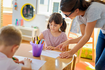 preschool teacher assisting children with their drawings. early education. harnessing creativity and