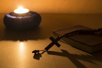 The bible and cross rosary beads on the wooden background with light lantern for blessed Sunday or Christianity . 