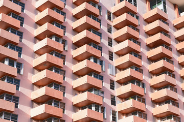 Wall Mural - Abstract pattern view on residential, apartment complex building with many windows, balconies painted in pink, orange during sunny day