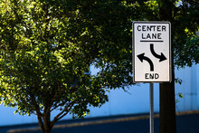 Center Lane Ends Sign With Trees, Road, And A Warehouse