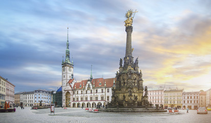 Wall Mural - Panorama of the Square and the Holy Trinity Column enlisted in the Unesco world heritage list and Astronomical clock in the building of the Town Hall in Olomouc, Czech Republic at sunset