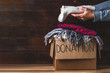 Donation concept. Donation box with donation clothes on a wooden background. Charity. Helping poor and needy people
