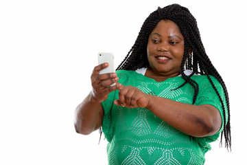 Studio shot of happy fat black African woman smiling and using m