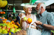 © NDABCREATIVITY - Smiling senior couple holding basket with vegetables at the market