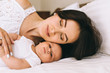 © LIGHTFIELD STUDIOS - beautiful smiling mother and child lying in bed at home