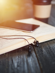 Coffee mug, headphones and a book. The concept of an audiobook and a modern electronic library