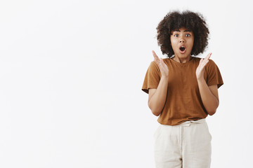 Wall Mural - excited and thrilled speechless african american young girl with curly hairstyle gesturing with palm