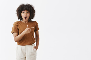 Wall Mural - indoor shot of impressed emotised good-looking young african girl with curly black hair dropping jaw
