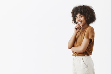 Wall Mural - intrigued flirty feminine dark-skinned female student with afro hairstyle in brown t-shirt standing 