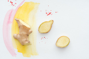 Wall Mural - top view of sliced ginger root on white surface with yellow watercolor strokes