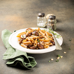 Wall Mural - Homemade whole grain pasta penne with fried mushrooms and thyme on white plate. Delicious healthy italian vegetarian food background. Copy space.