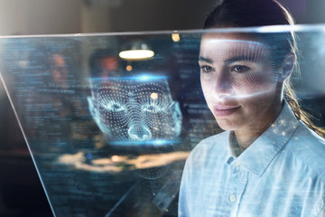 Portrait of a beautiful woman (girl) while she is looking at a futuristic screen with holograms and the office in the background. Concept: Future, Technology, work