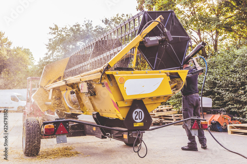Fotografía The mechanics repair the yellow combine harvester in the farm yard