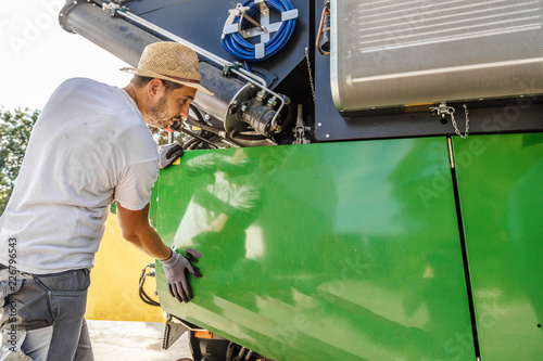 Cuadros en Lienzo The mechanics repair the yellow combine harvester in the farm yard