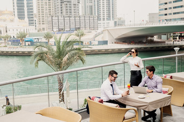 Business meeting on modern balcony in Dubai Marine . Three people representing their companies and talking about cooperation.