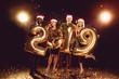 happy friends in santa hats holding 2019 new year golden balloons on confetti