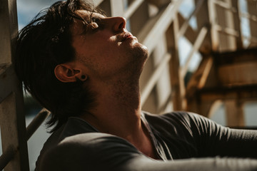 Handsome man sitting on the staircase with eyes closed