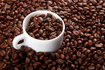 Mug full of, and surrounded by, coffee beans