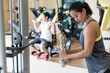 Side view of a determined young woman exercising cable rope triceps extension during upper-body workout routine in a modern fitness club