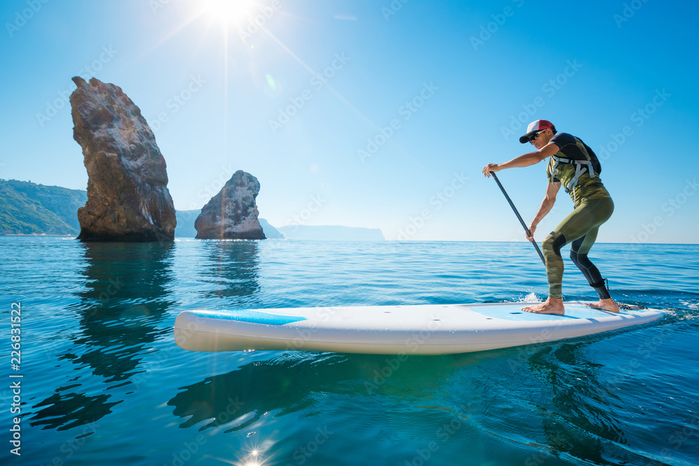 Subboarding Stand up paddle boarding. Young man floating on a SUP board. The ...