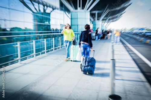 Plakat Ludzie chodzą przed lotniskiem z bagażem