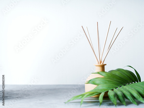 Fotografía aroma reed diffuser home fragrance with rattan sticks on a light background with palm leaves and shadows