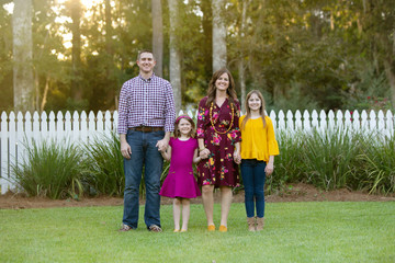 Wall Mural - Family of Four Holding Hands Outside of Home with White Picket Fence