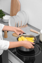 Sticker - Woman preparing corn in stewpot on stove, closeup