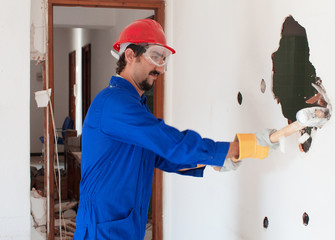 young worker with a red protection helmet and wearing a blue boiler suit. demolition concept