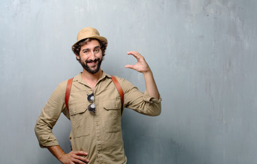 young traveler man or tourist smiling with a satisfied expression showing a small object or concept, holding it with single hand.