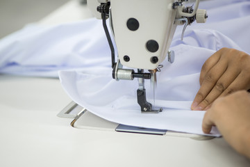 Wall Mural - seamstress on a sewing machine makes a shirt in the sewing workshop. the woman on the machine sews the collar and cuffs