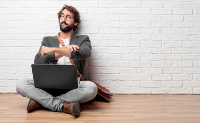 young man sitting on the floor with a proud, happy and confident expression; accepting a challenge with arms crossed, smiling and sure of success, giving an 