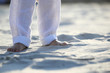bare feet of a child in white pants on the sand