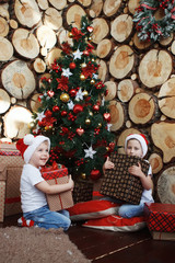 Two brother boys around a Christmas tree.