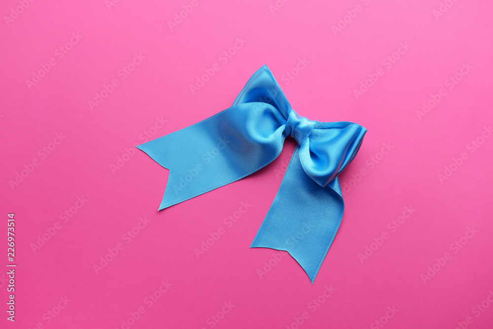 Beautiful bow made of blue ribbon on color background