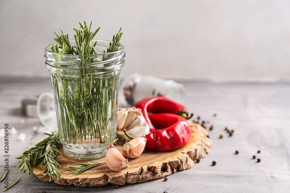 Jar with fresh rosemary on wooden board