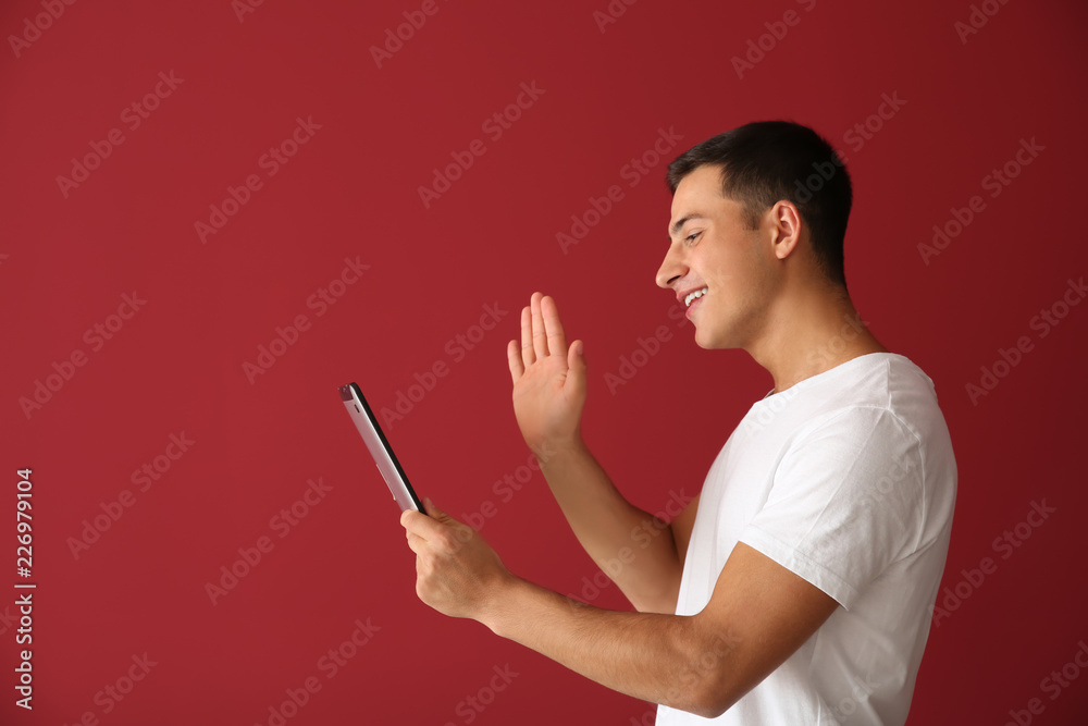 Young man with tablet computer having online dating, on color background