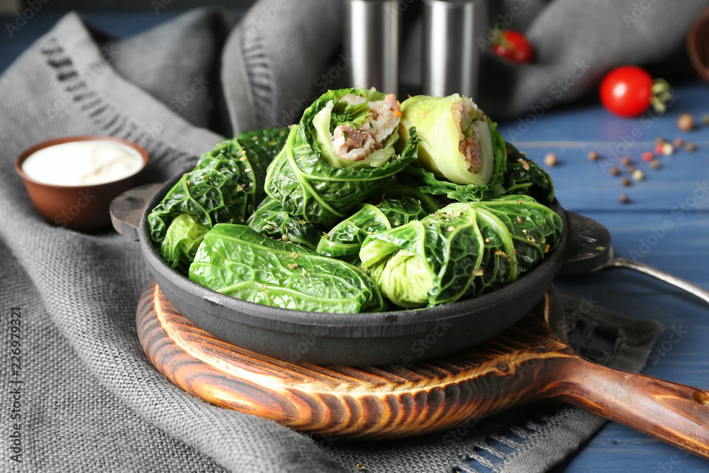 Pan with stuffed cabbage leaves on wooden board - obrazy, fototapety, plakaty 