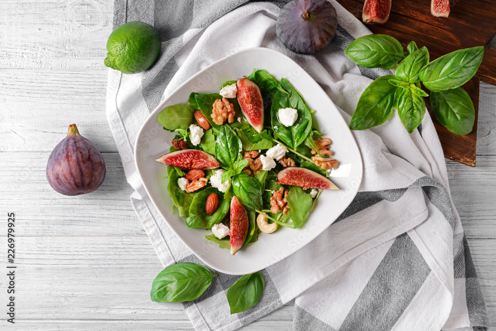 Plate with delicious fig salad on light wooden table