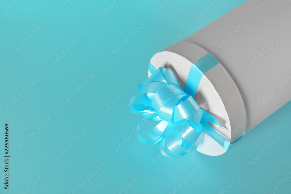 Gift box with blue ribbon on color background