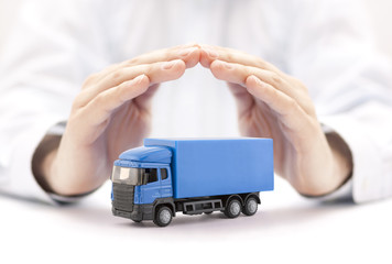 Poster - Car insurance. Blue truck miniature covered by hands.