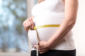 Pregnant woman measuring her belly