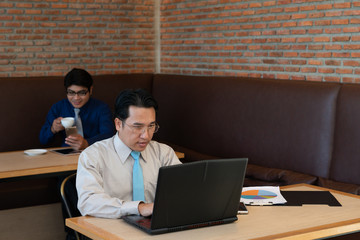 Poster - Asian businessmen using laptop surfing the Internet in a cafe