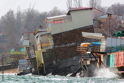 Fotografía Coastal erosion - houses built on weak clay soil slide down to the sea and colla