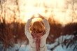 Девушка ловит солнце руками зимой на закате