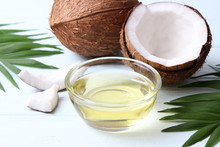 Coconuts And Coconut Oil With Tropical Leaves On A Wooden Background