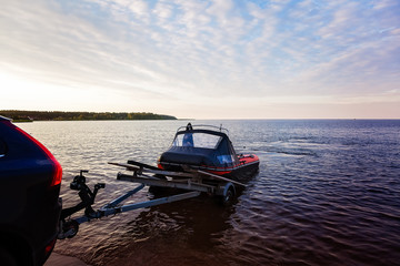 Wall Mural - Loading a rubber boat on a trailer on the lake at sunset