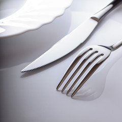 Wall Mural - Empty plate with knife and fork on a white background