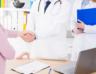 male hand of the doctor shakes the female arm of his patient in clinic, medical office. Healthcare concept, health insurance