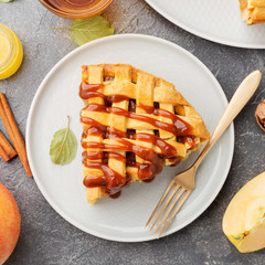 Wall Mural - Slice of apple pie with caramel sauce on a  plate. Grey background. Close up. top view.